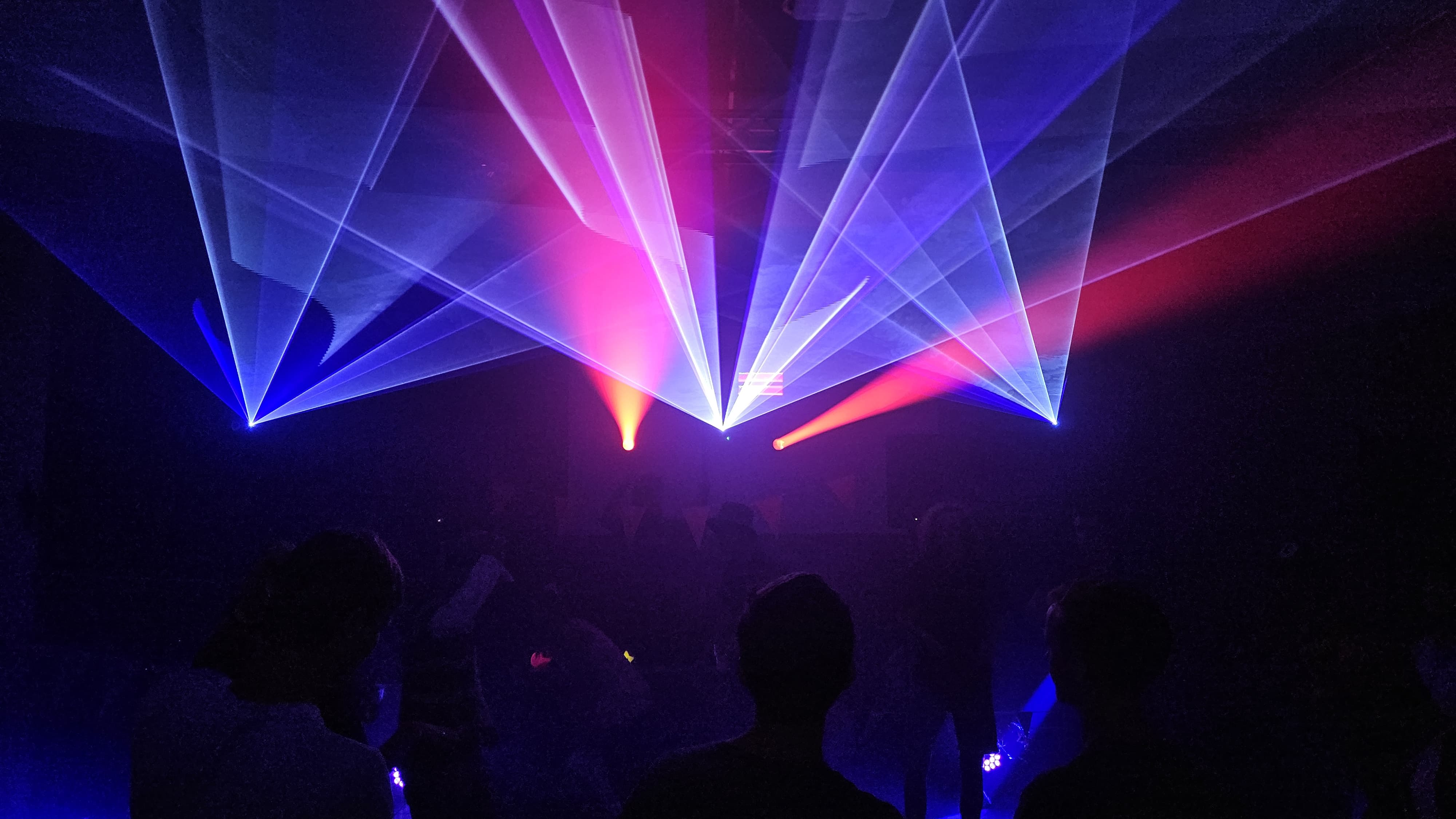 Zelfgebouwde lasershow, meerdere gekleurde stralen boven een dansvloer